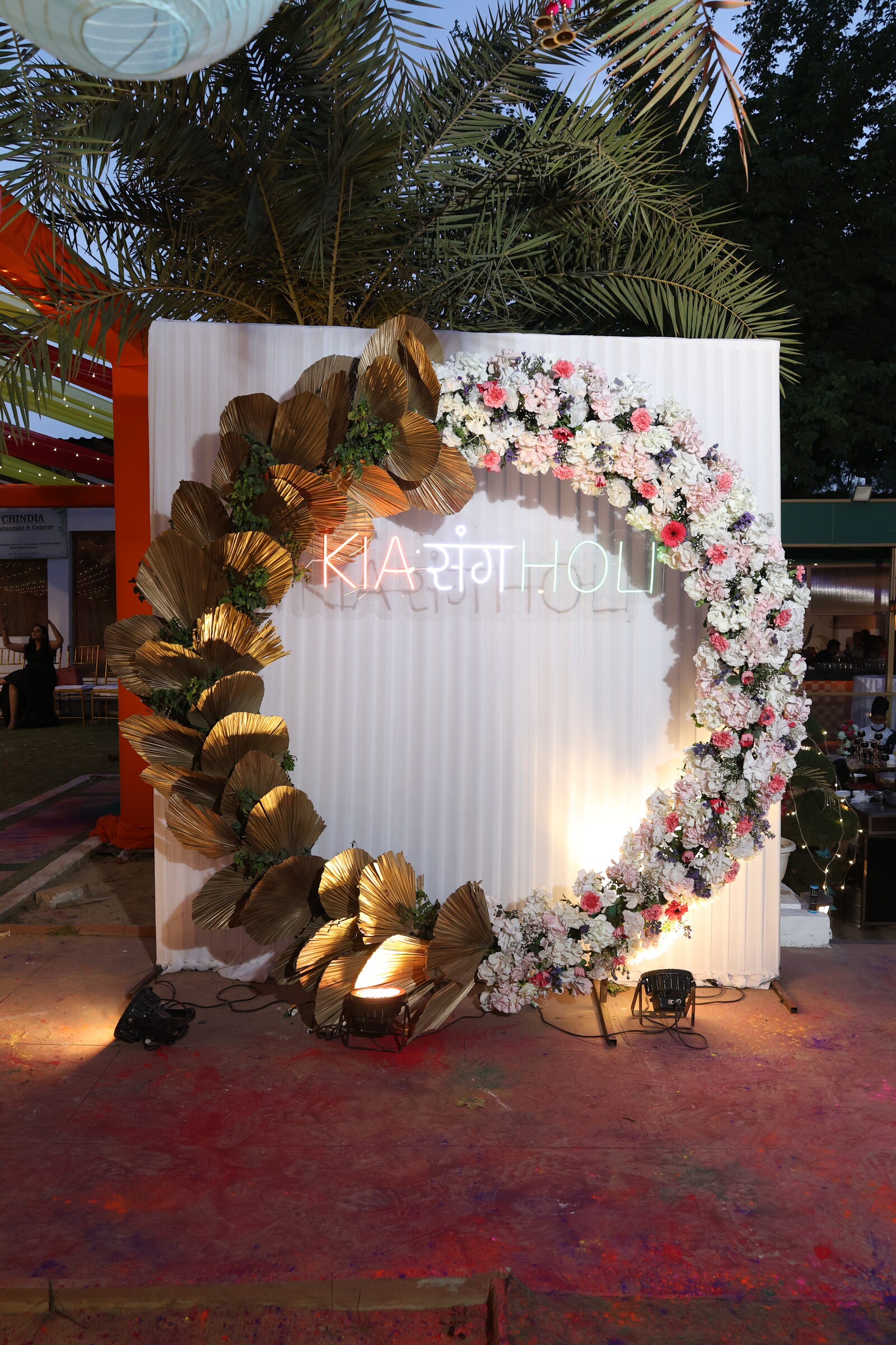 A floral celebration backdrop illuminated for an evening gathering