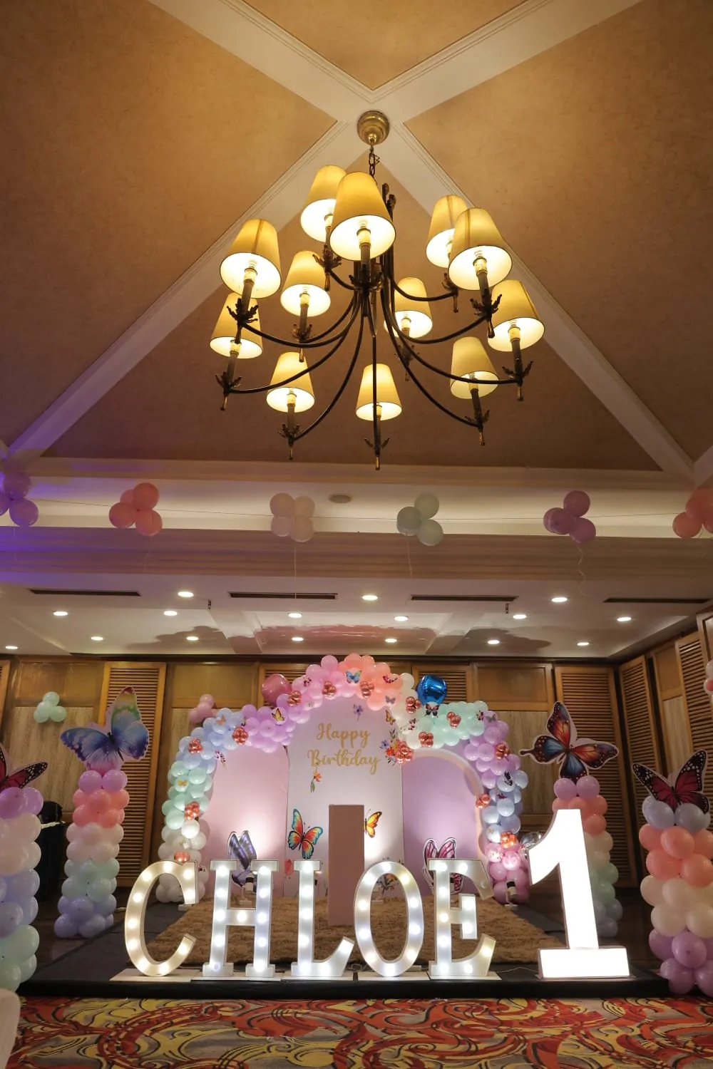A pastel balloon ceiling and birthday stage prepared in a hall