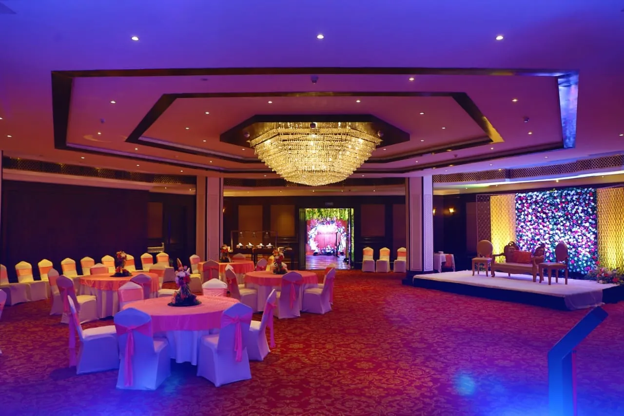 A corporate event ballroom set with guest tables and stage lighting