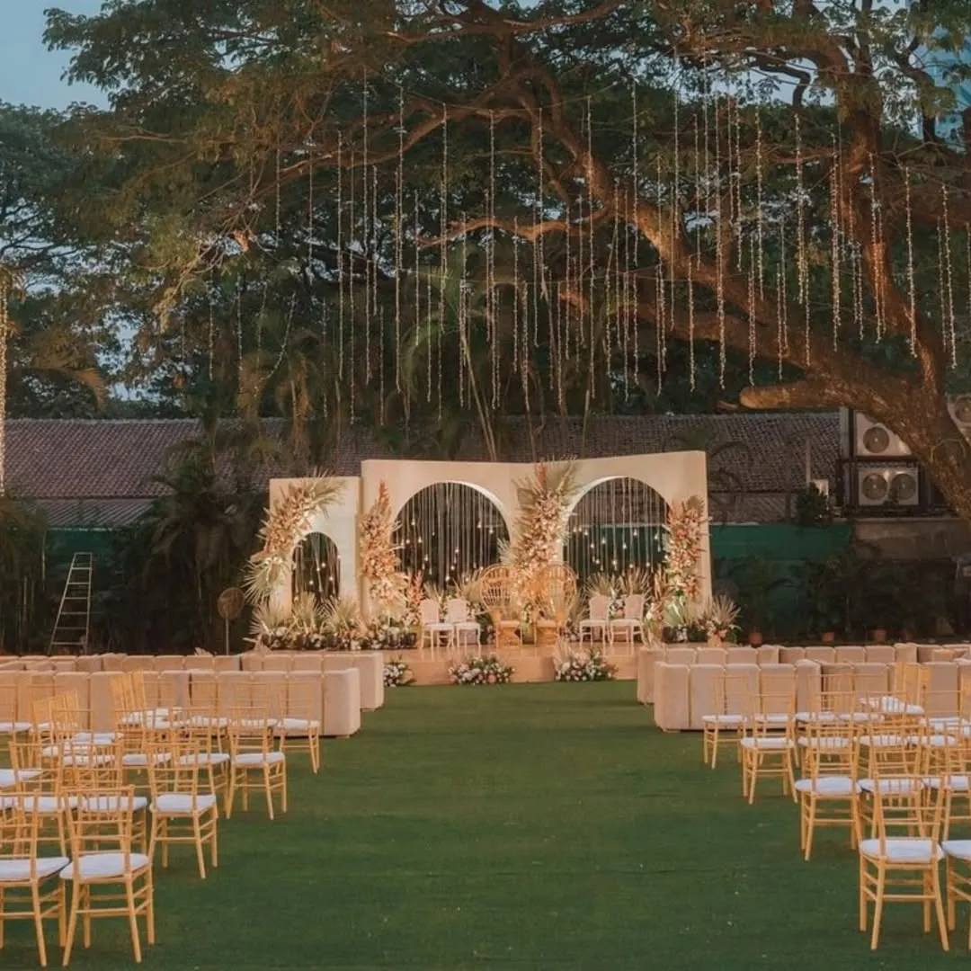 An outdoor wedding aisle leading to a floral ceremony backdrop