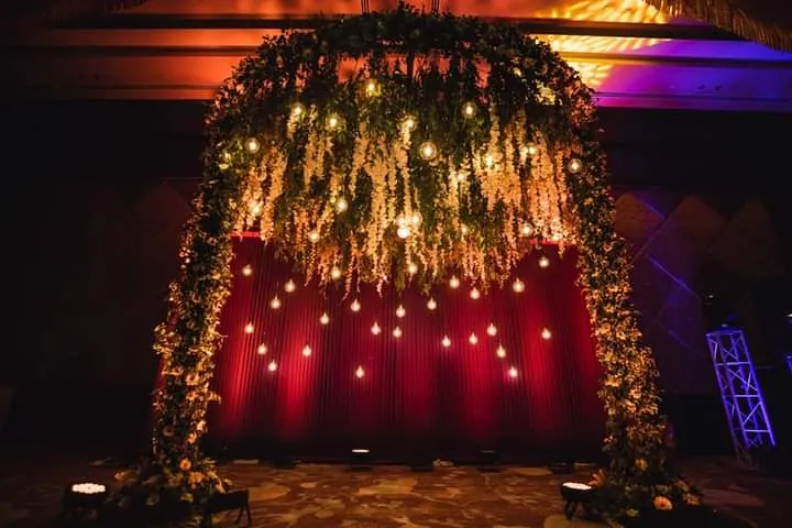A flower-filled event arch lit for an evening celebration